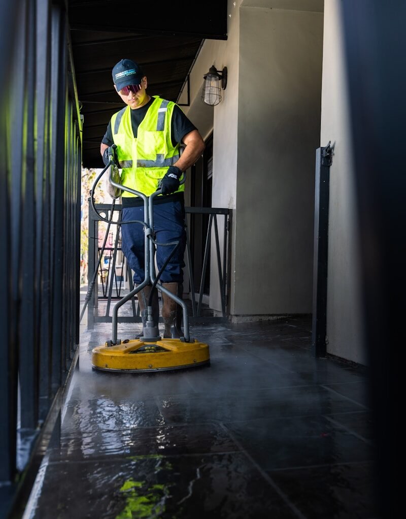 a man in a yellow vest is cleaning the floor